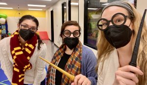 OT grad student Liz, OT Christina and SLP Laura holding wands and wearing Harry Potter glasses and Hogwarts' scarves during potions class at The Hello Clinic.