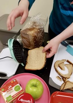 Child putting bread in waffle iron at The Hello Clinic.
