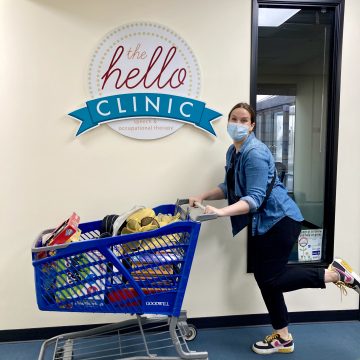 OT Emily pushing a shopping cart of toys and games at The Hello Clinic.